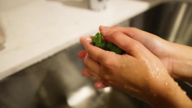 Eller akan suyun altında çilek yıkıyor.