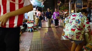 Hareketli tezgahları, hareketli müşterileri ve renkli vitrinleri olan Bangkok çiçek pazarı. Akşam ışığı sıcak, davetkar bir atmosfer yaratır.