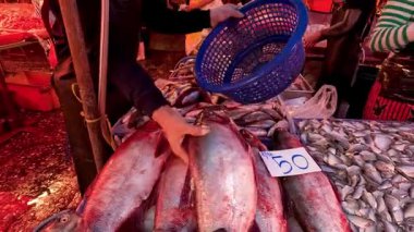 Meşgul bir pazarda satıcı balık tutuyor