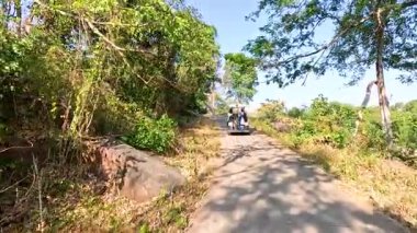 Golf arabası manzaralı bir dağ yolunda ilerliyor.