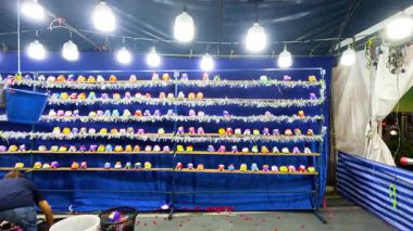 Bangkok 'ta hareketli bir gece marketinde parlak yukarıdaki ışıklarla aydınlatılmış canlı bir oyuncak bebek atış kulübesi var.