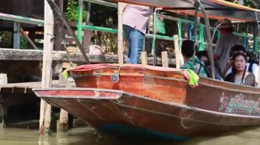Uzun kuyruklu botlar Bangkok, Tayland 'da canlı yüzen bir pazarda süzülüyor. Parlak renkler ve hareketli aktivite canlı bir atmosfer yaratır.