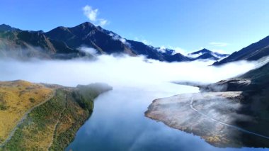Queenstown, Yeni Zelanda 'daki dağlarla çevrili Moke Gölü' nün üzerindeki sis manzarası. Parlak gün ışığı dingin atmosferi güçlendirir.