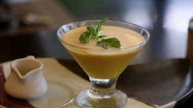 Bir kaşık nane şekeriyle süslenmiş kremalı mango kremasına batar ve lezzetli bir tatlı deneyimini ön plana çıkarır.