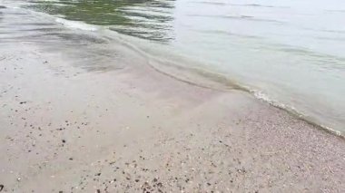 Dalgalar yumuşak bir şekilde kumlu kıyıya vurur