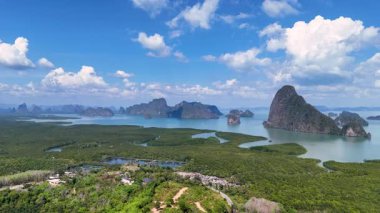 İnsansız hava aracı görüntüleri, açık mavi gökyüzü altında Tayland 'ın Phang Nga Körfezi' nin çarpıcı kireçtaşı adalarını ve yemyeşil yeşilliklerini yakalıyor.