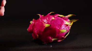 Siyah arka planda suyla sislenmiş ejderha meyvesi