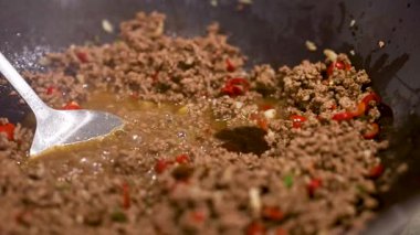 Tavada canlı biberlerle kızartılmış biftek ve fesleğen, sıcak mutfak ışıkları altında, dinamik yemek pişirme eylemi sergileniyor.