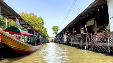 Tekneler kanal boyunca hareketli pazarlarda gezinirler.