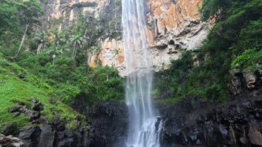 Şelale kayalık bir uçurumdan aşağı yuvarlanıyor.