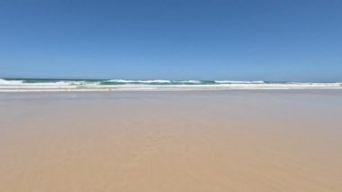 Sakin okyanus dalgaları yavaşça kumlu kıyıya yaklaşıyor