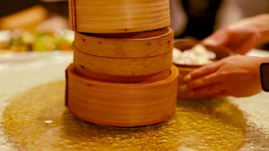 Eller, ortam aydınlatmalı sıcak ve davetkar bir restoran ortamında bambu budan yapılma buharlı lokum servis eder.