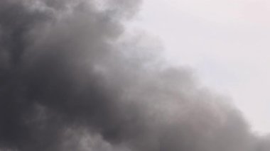 Yoğun, karanlık duman, dinamik bir şekilde aydınlık gökyüzüne vurarak dramatik ve karamsar bir atmosfer yaratır.