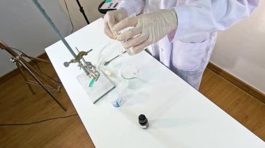 Bir bilim adamı laboratuvar ortamında bakır karbonat ve sülfürik asit arasında kimyasal bir reaksiyon gerçekleştiriyor.