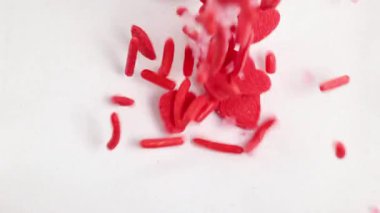 Kırmızı şeker kalpler ve serpintiler beyaz bir yüzeye dökülür, canlı ve eğlenceli bir görsel etki yaratır.