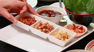 Miang Kham için malzemeleri tepside hazırlayan eller. Parlak ışıklandırma Tayland mutfağındaki canlı renkleri ve dokuları vurgular