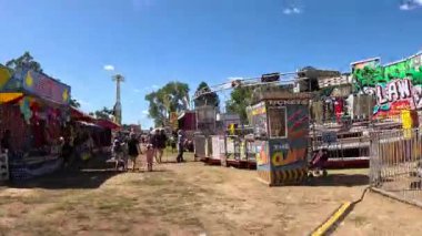 Ziyaretçiler güneşli bir panayırda çeşitli eğlencelerin tadını çıkarıyorlar