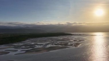 İnsansız hava aracı, altın bir günbatımının altında doğal güzellik ve sükuneti ön plana çıkaran sakin mangrovları ve nehri yakalıyor.