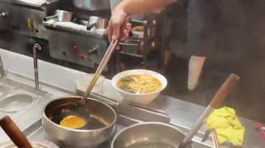 Şef çorbayı erişte kasesine koyuyor.