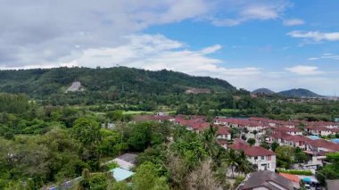 Drone görüntüleri Phuket 'teki bir golf sahasının manzaralı bir üst geçidini yakalıyor, açık gökyüzü altında yemyeşil ve lüks villalar sergiliyor.