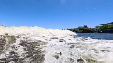 Okyanus dalgaları açık gökyüzünün altında kıyıya yaklaşıyor.