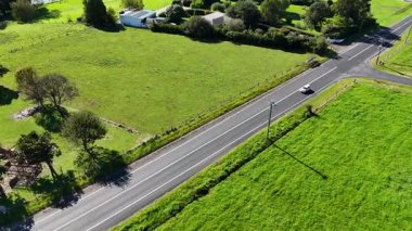 Hava görüntüleri, Dorrigo, NSW 'de verimli yeşilliklerle çevrili kırsal bir yolda seyahat eden araçları parlak güneş ışığı altında yakalıyor.
