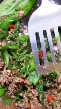 Bir tavada et ve fesleğen kızartması yakın plan, canlı renkler, dinamik spatula hareketleri, parlak ışıklandırma