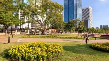 Şehir silueti olan bir parkta yürüyen insanlar.