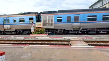 Bir adam Kanchanaburi, Tayland 'daki bir istasyona giden trene yetişmek için koşar. Parlak gün ışığı ve dinamik hareket yakalandı