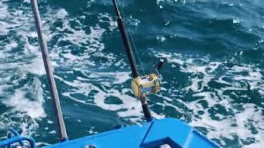 Phuket 'in okyanusundaki bir teknede olta kamışı, parlak güneş ışığı altında dinamik su hareketlerini yakalıyor.