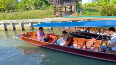 Bir kanal teknesi Khlong Lat Mayom Yüzen Pazarı 'nda yüzüyor, Bangkok' ta canlı bir manzara ve yerel kültür sergiliyor.