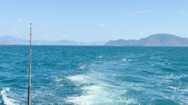 Tayland, Phuket yakınlarındaki okyanusta açık mavi gökyüzünün altında görülebilen uzak adaları olan bir tekne bir uyanış yaratıyor.