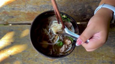 Yemek çubuğu ve kaşıkla erişteyi seven kişi