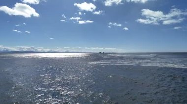 Byron Körfezi 'nin engebeli kıyı şeridinin hava manzarası. Dalgalar parlak mavi gökyüzünün altında kayalara çarpıyor.