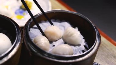 Yemek çubukları buhardan karides köftesi topluyor.