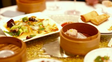 Masada canlı bir Dim Sum tabağı gösterisi. Geleneksel Çin mutfağını sıcak ve davetkar bir ortamda ön plana çıkarıyor.
