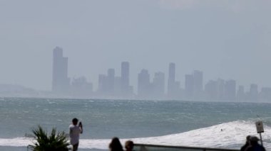 Sörfçüler dalgalara biner şehrin ufuk çizgisi arkaplanıyla