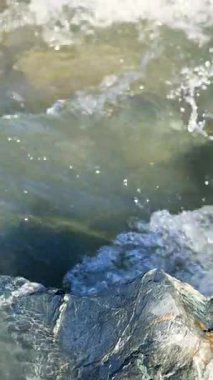 Dinamik dalgalar parlak güneş ışığı altında kayalık kıyılara çarpar ve Wakatipu Gölü 'nün doğal güzelliğini ve gücünü yakalar.