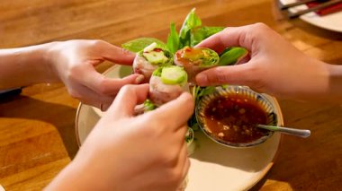 Bangkok 'ta bir restoranda Vietnam usulü domuz eti hazırlayıp sosa batırmak. Parlak ışıklandırma canlı ve taze malzemeleri geliştirir.