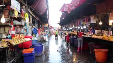 Islak bir pazarda satıcılar ve müşteriler