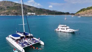 Katamarlılar, Phuket 'in turkuaz sularında, berrak gökyüzünün altında süzülerek, sakin bir tropikal sahneyi, nazik kamera hareketleriyle yakalıyorlar.