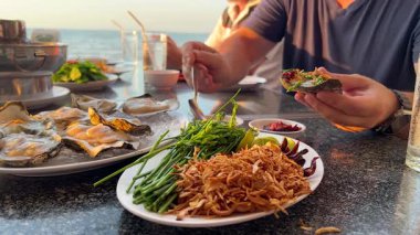 Deniz kenarındaki istiridye ve deniz ürünlerinin tadını çıkarıyorum.