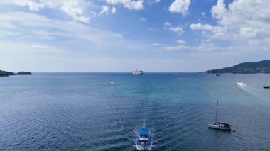 Phuket, Tayland yakınlarındaki berrak mavi sularda yüzen teknelerin parlak bir gökyüzünün altındaki hava manzarası.
