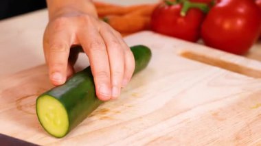 Kesme tahtasında bıçakla salatalık dilimlemek