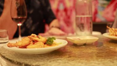 Tembel bir Susan yemek, şarap ve renkli dekor ile bir restoran masasında döner, canlı bir yemek atmosferi yaratır.