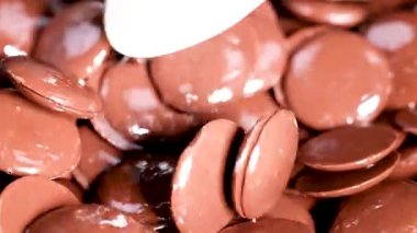 Kaşık hareketli parlak çikolata disklerini karıştırıyor