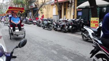 Turistler kalabalık Hanoi caddesinde bisiklet sürmekten zevk alıyorlar
