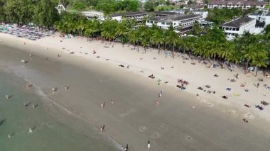 İnsansız hava aracı görüntüleri Phuket, Tayland 'da canlı şemsiyeler, güneşli banyolar ve verimli yeşillikleri gün ışığında gözler önüne seriyor.