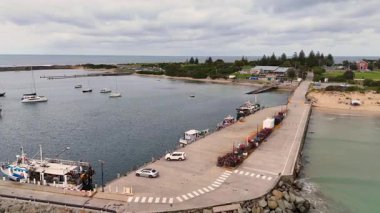 İnsansız hava aracı görüntüleri Lorne 'un manzaralı limanını, teknelerini, rıhtımını ve kıyı şeridini bulutlu gökyüzünün altında yumuşak kamera hareketleriyle yakalar.