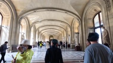 İnsanlar büyük bir müze koridorunda yürüyor.